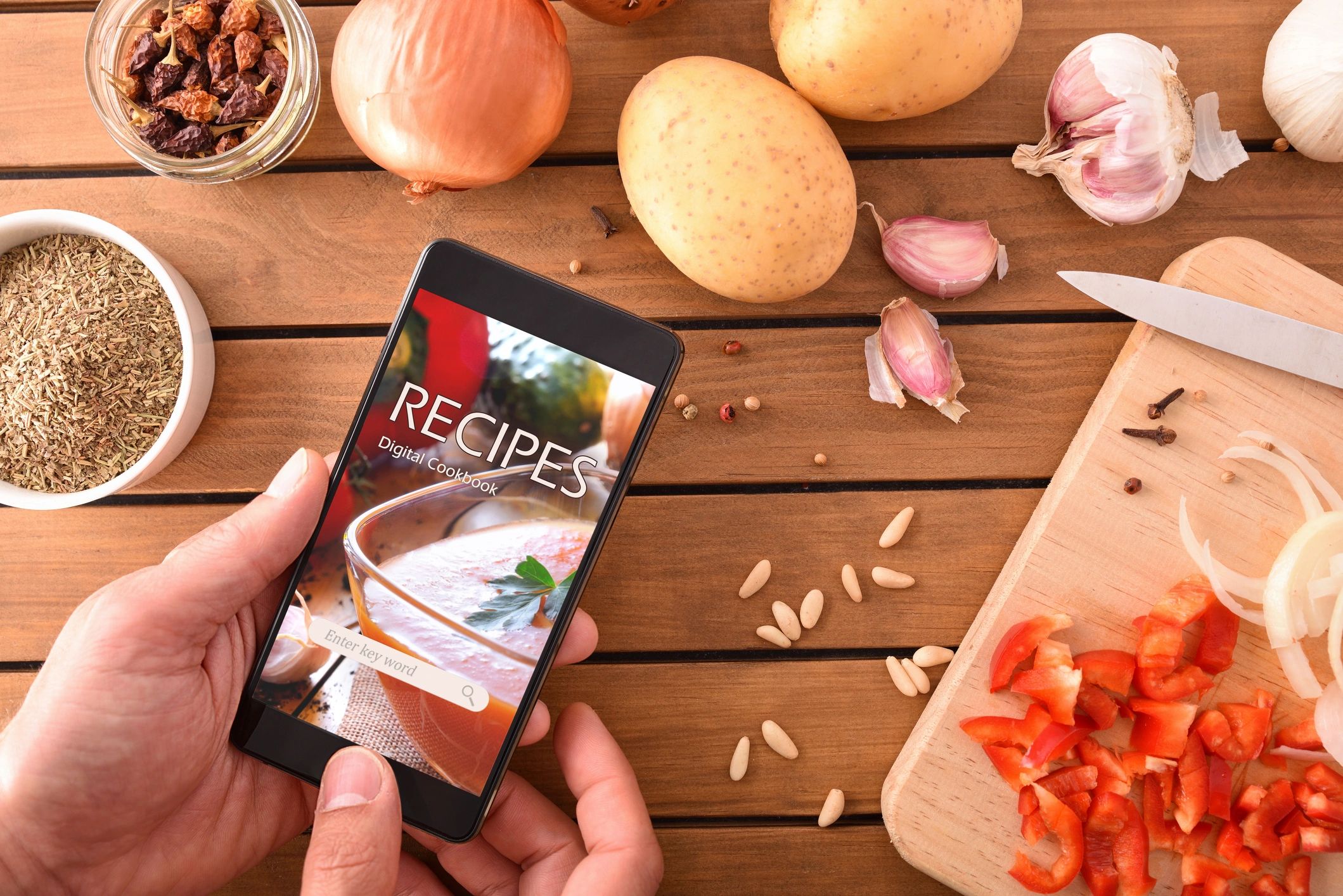 Smartphone with online recipes app and ingredients background.